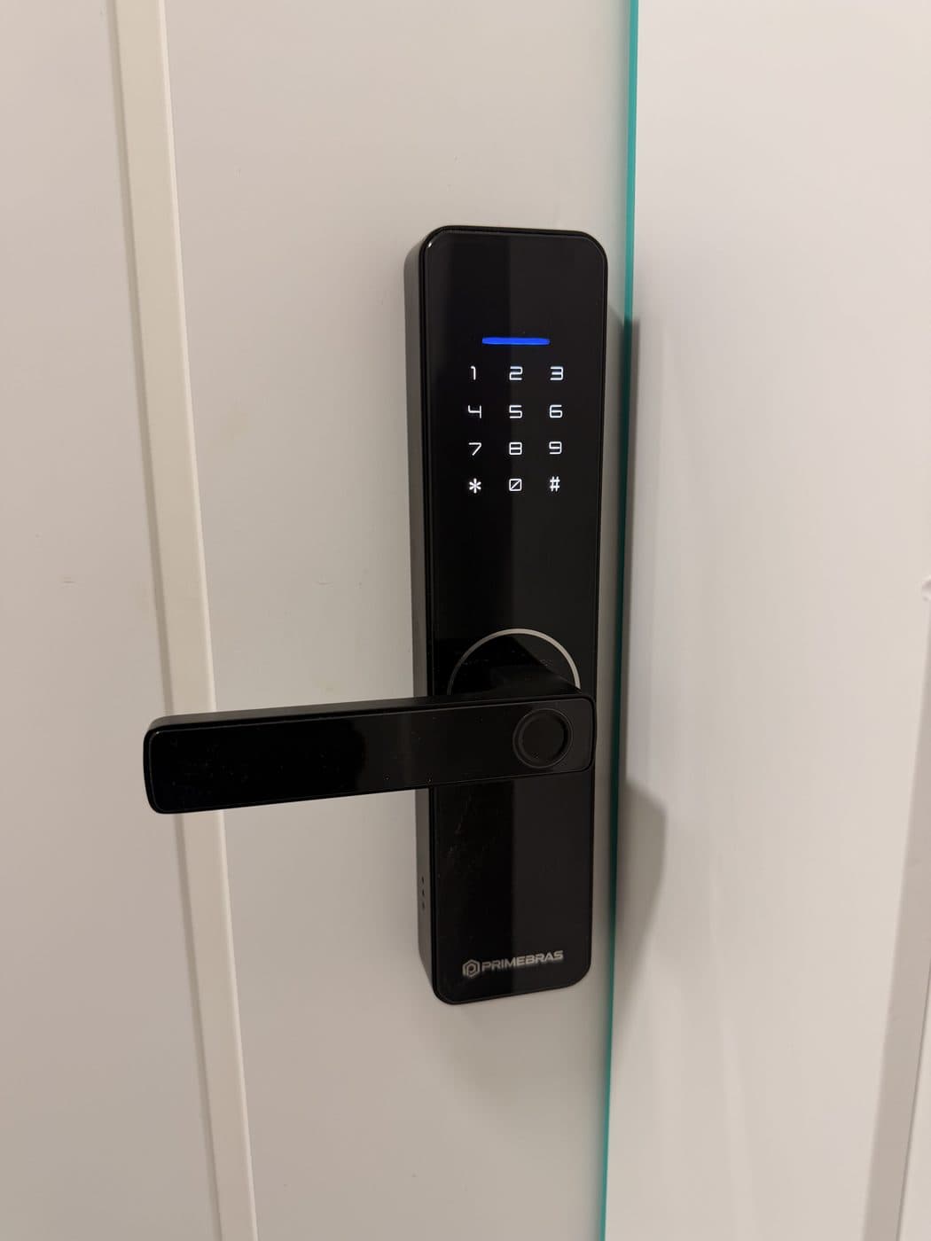 Fechadura eletrônica com senha e biometria instalada em porta branca